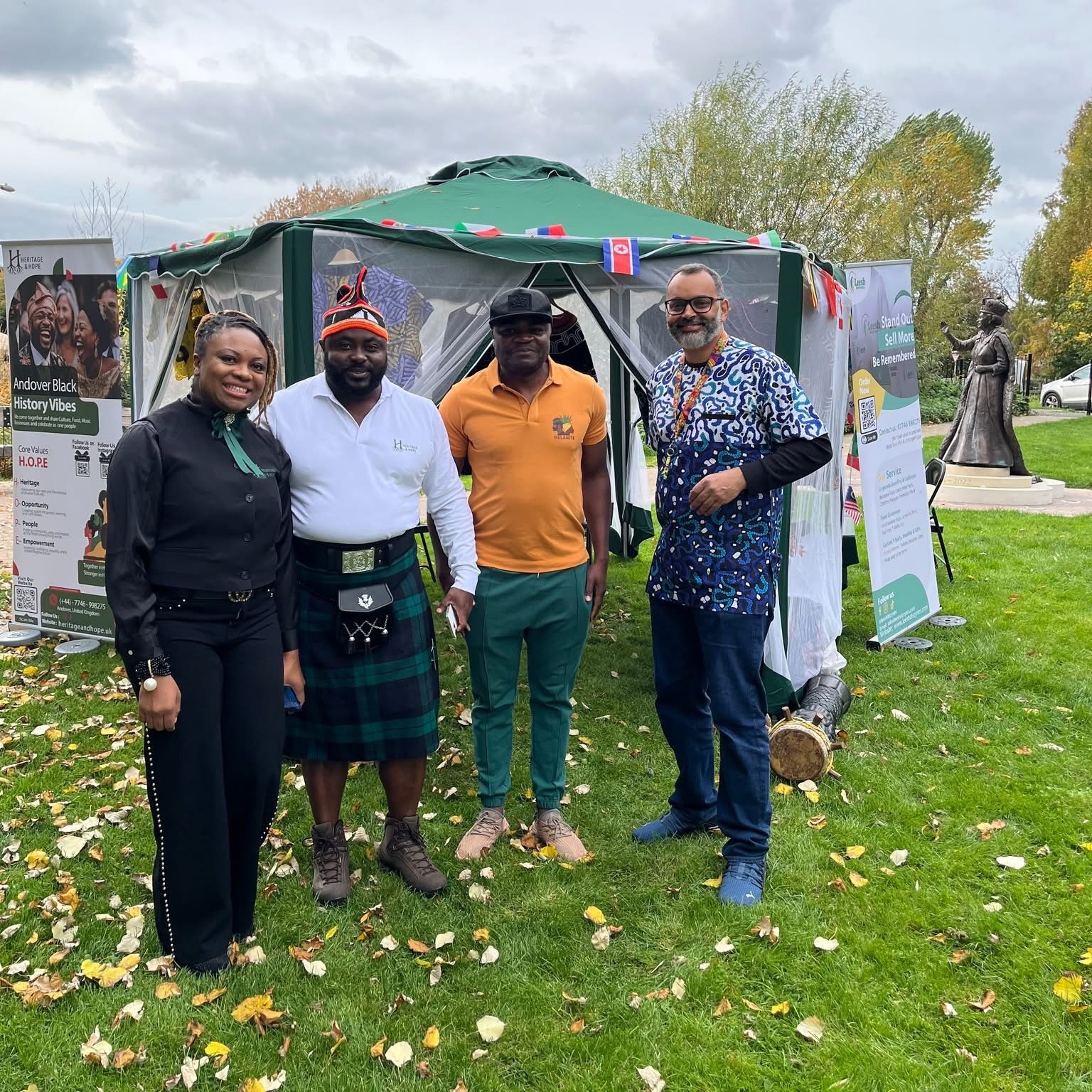 The Heritage & Hope team outside the event gazebo with international flags