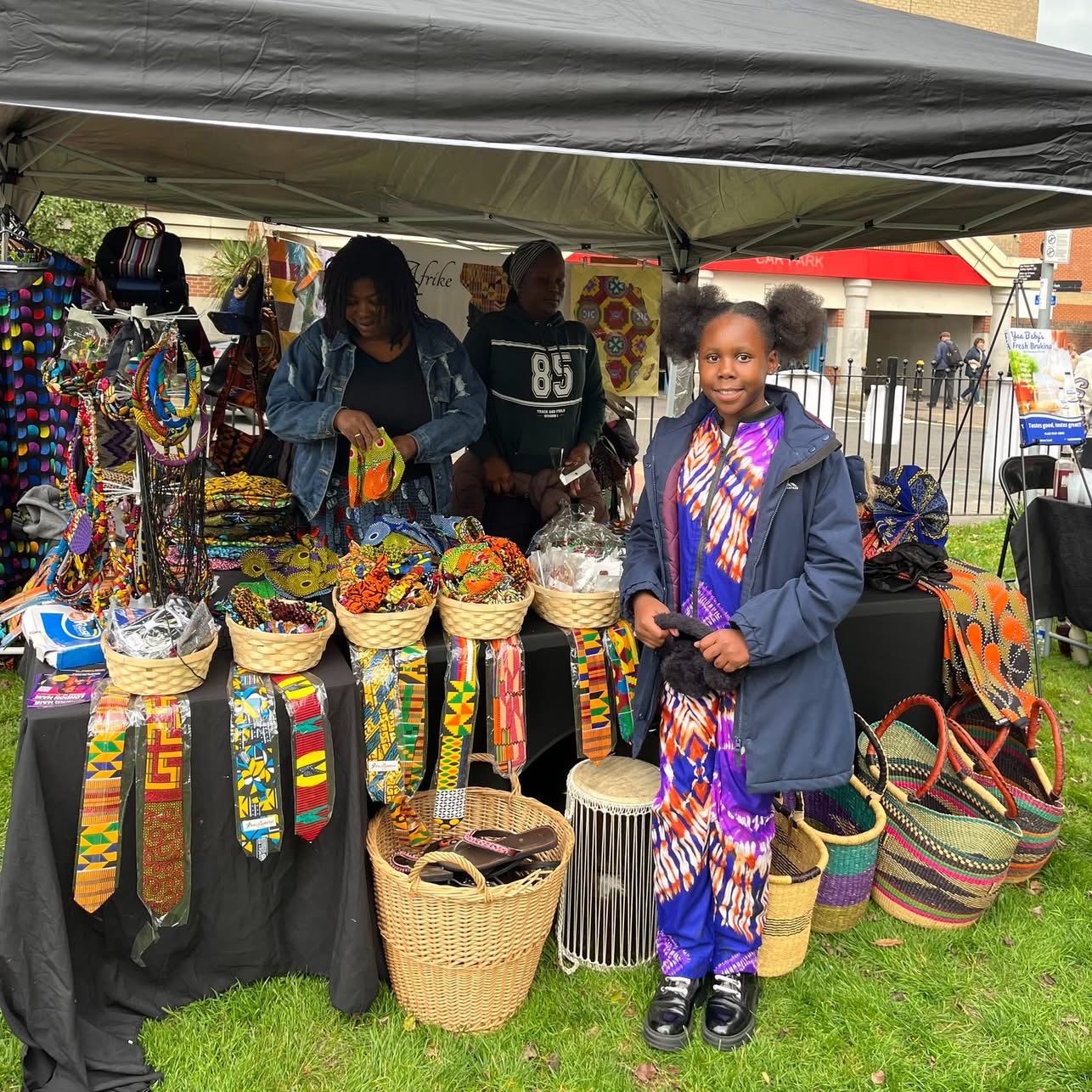 A young girl beside a colourful African craft and textiles stall
